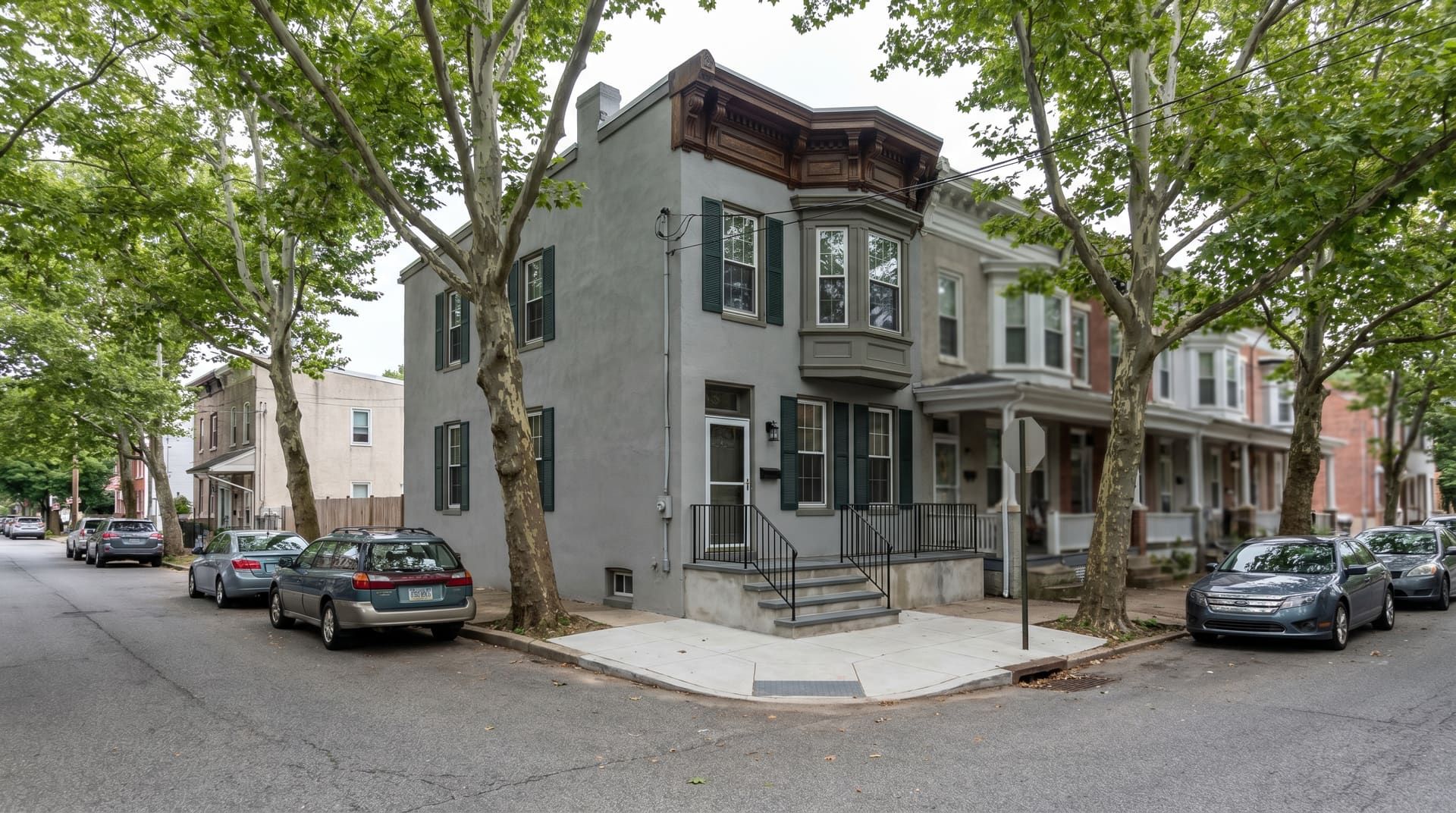 1890s Victorian rowhouse with elaborate cornice trim and bay window on a tree-lined Norristown West End street, with a freshly rebuilt bluestone-clad stoop and wrought-iron handrail