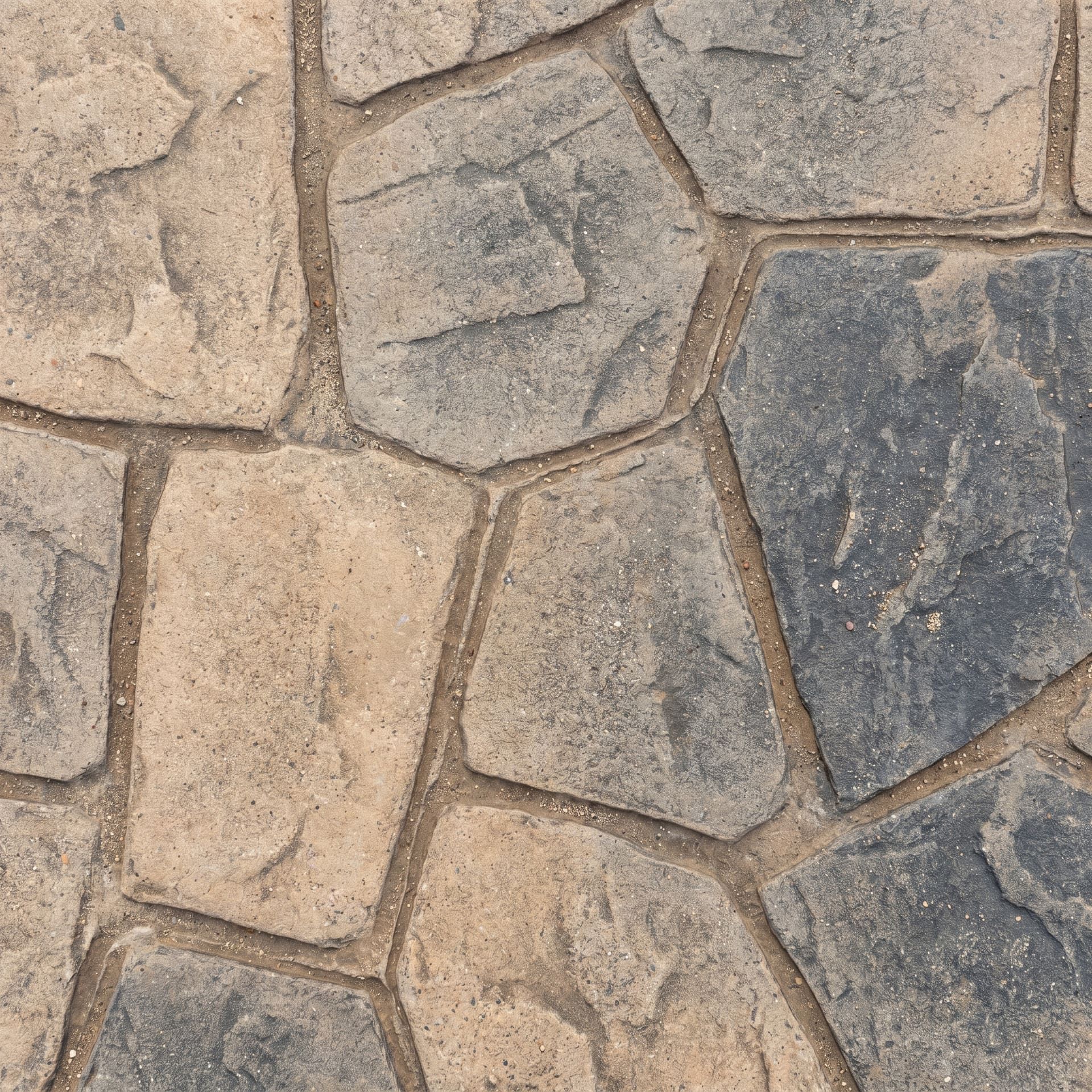 Close-up detail of stamped concrete patterned to look like irregular ashlar slate with crisp recessed grout joints between blue-gray and tan stone faces